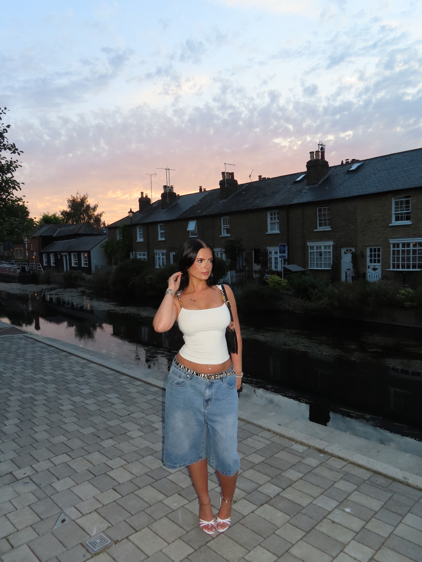 Charlotte Williams photographed at dusk beside a canal in a white vest and denim