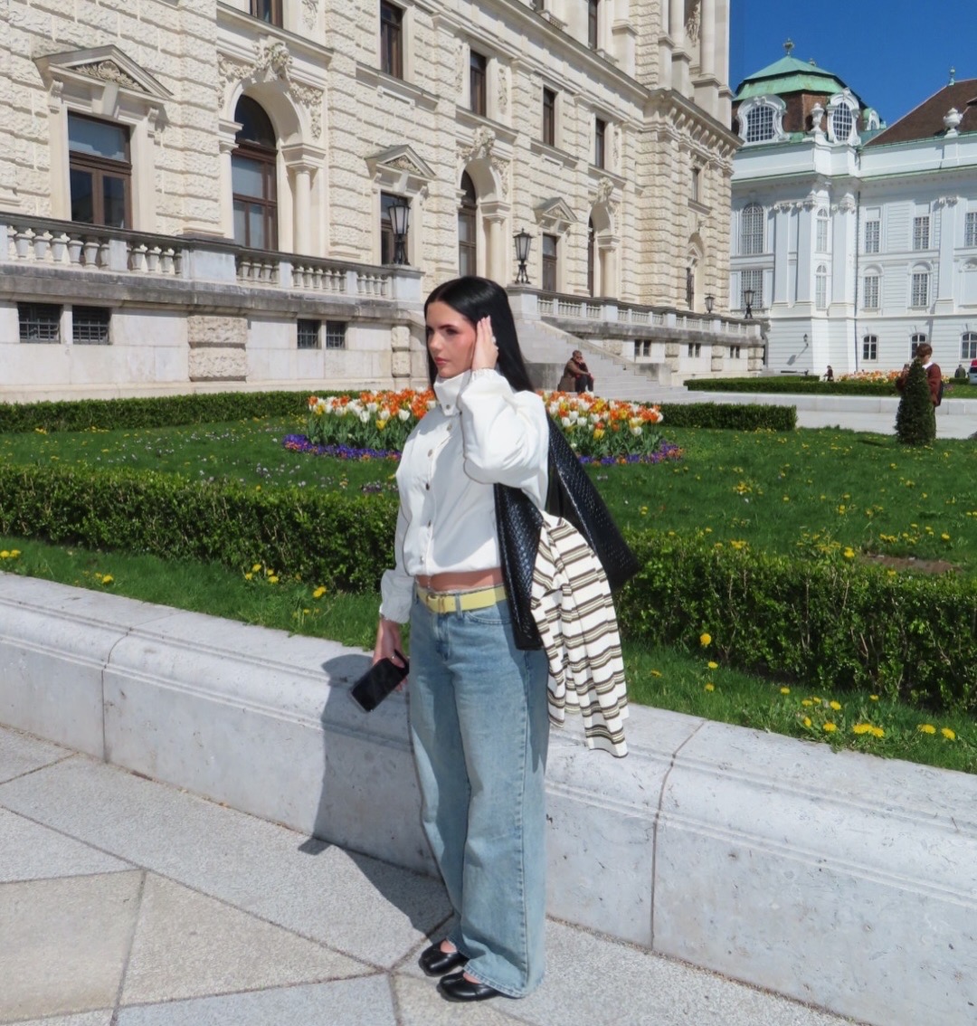 Charlotte Williams photographed outside a Viennese palace in a white jacket and denim