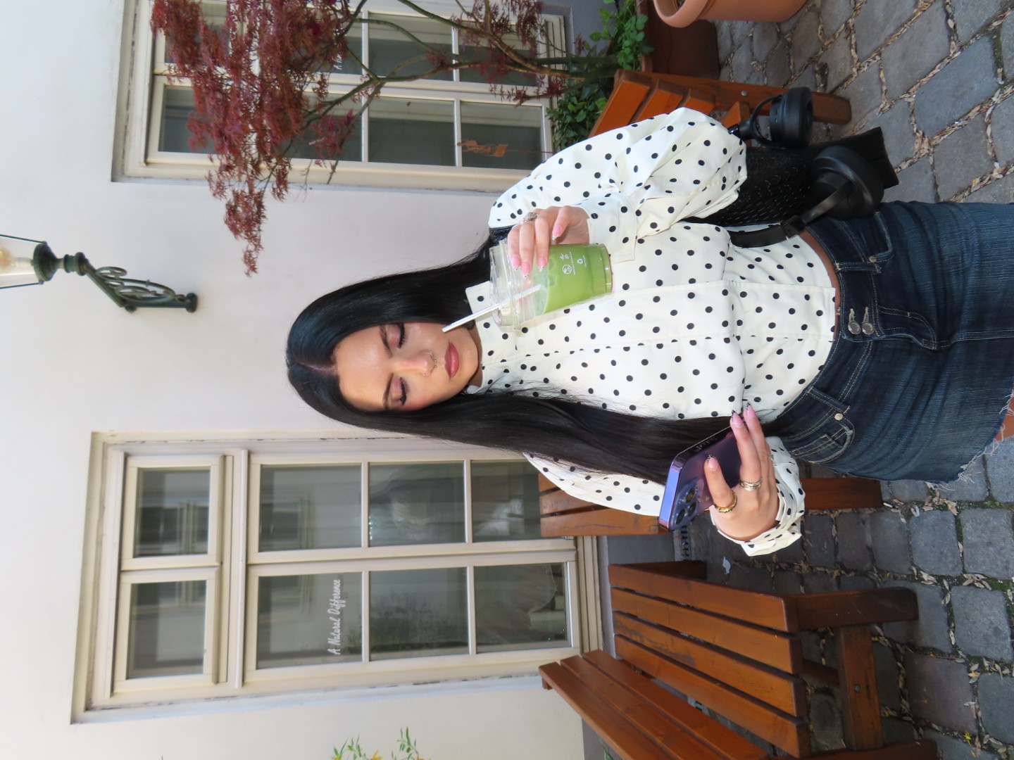 Charlotte Williams in a polka-dot blouse and denim skirt on a cobbled street